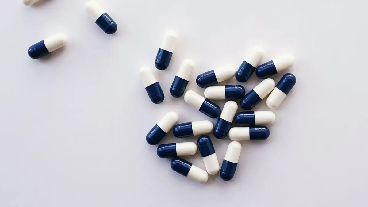 Several supplement bottles and loose capsules arranged on a kitchen counter